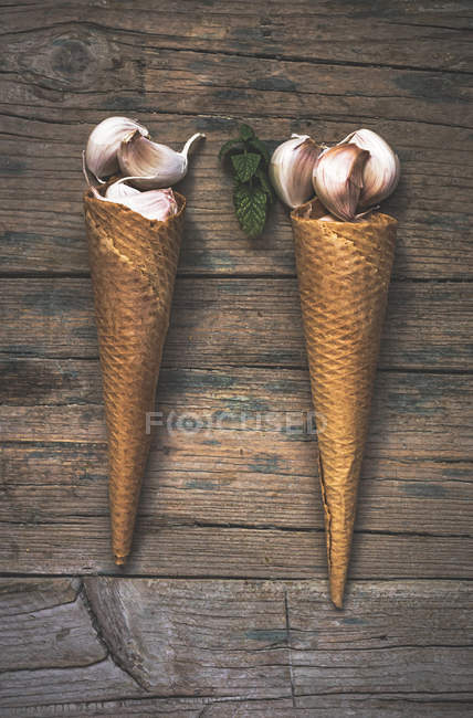 Arrangement of garlic and waffle cones on rural table — Stock Photo