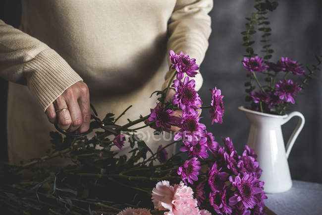 Середина жіночого флориста, що ріже ножицями букет квітів на столі — стокове фото