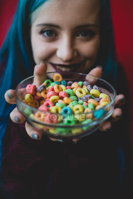 Happy girl holding bowl of colored flocks. — Stock Photo