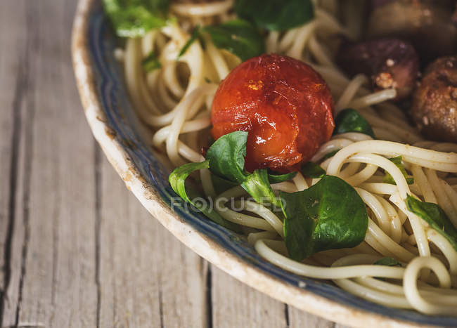 Close up view of cherry tomato and basil leaves on plate with pasta — Stock Photo
