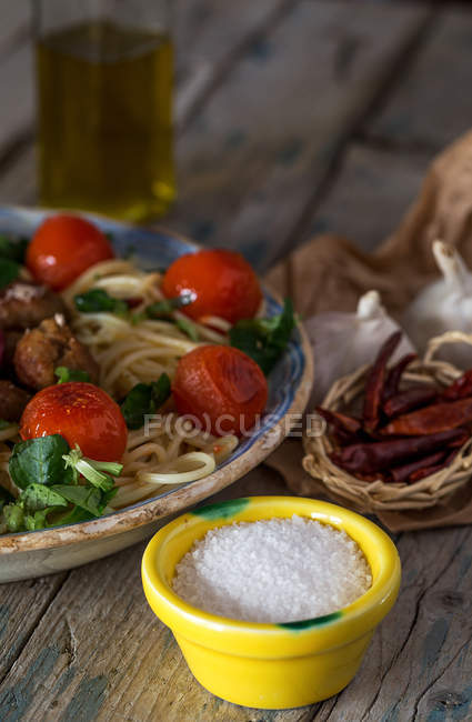 Vista de cerca de cuencos pequeños con sal y pimienta cerca de plato de espaguetis - foto de stock