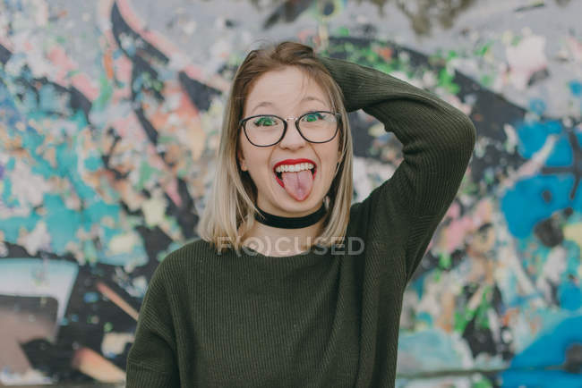 Fille blonde dans les lunettes de mettre la langue dehors — Photo de stock