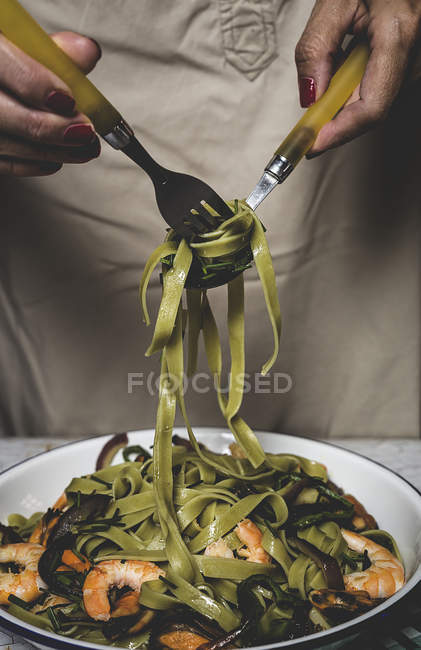 Crop female winding italian green tagliatelle on fork — Stock Photo