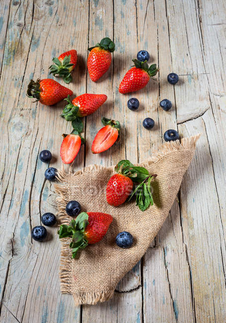 Mélange de fraises et de bleuets sur une vieille table en bois — Photo de stock