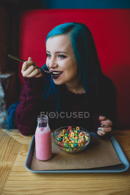 Chica con pelo azul comer bandadas - foto de stock