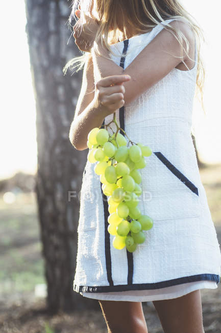 Midsection of child girl holding green grape — Stock Photo