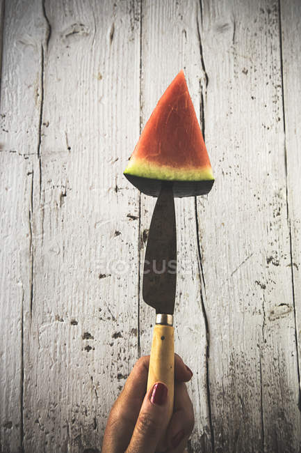 Nahaufnahme einer weiblichen Hand, die ein Messer mit der Hälfte einer frischen Wassermelone hält — Stockfoto