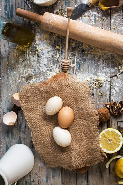 Bodegón de ingredientes y utensilios de panadería en mesa de madera rural - foto de stock