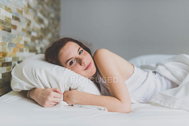 Süßes Mädchen mit Sommersprossen wacht im Bett auf — Stockfoto