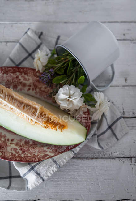 Leckere Melone und Tasse mit Blumen auf ländlichem Tisch — Stockfoto
