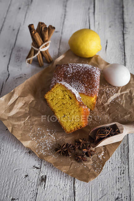 High angle view of homemade cake slices on bakery paper with ingredients on rural table — Stock Photo