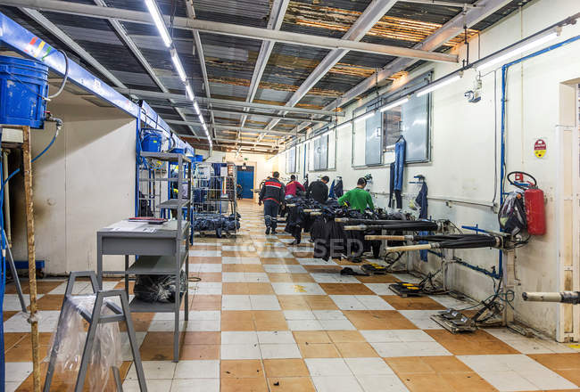 Clothing company manufacturesTANGIER, MOROCCO- April 18,2016: Industrial sewing machines in line and workers at clothing manufactures — Stock Photo