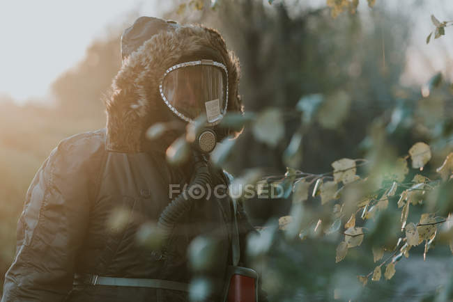 Retrato de homem vestindo capa e máscara de gás andando no campo rural — Fotografia de Stock