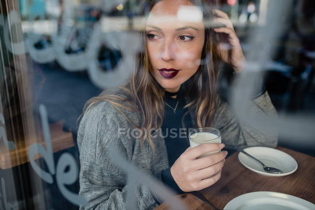 Femme buvant du lait dans une bonneterie . — Photo de stock