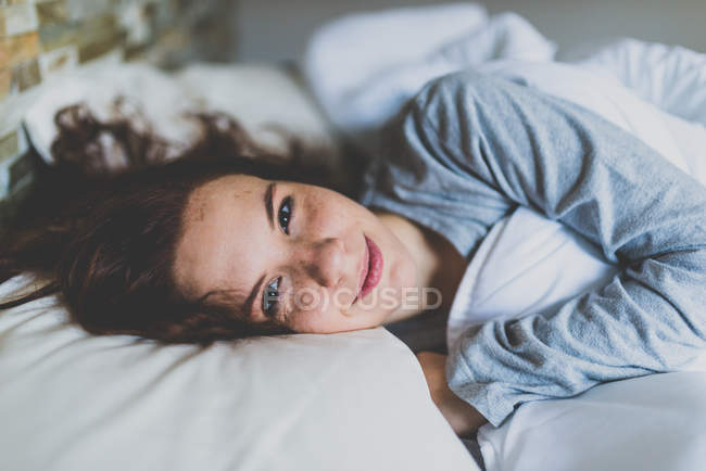 Donna sul cuscino a letto e sorridente — Foto stock