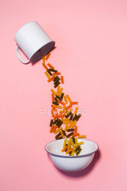 Pasta falling from cup to bowl — Stock Photo