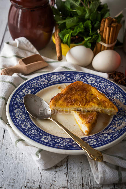 Bodegón de plato con tostadas dulces y utensilios de cocina sobre mesa de madera - foto de stock