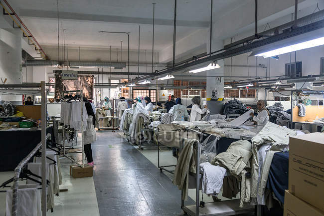 Tánger, MARRUECO- 18 de abril de 2016: Vista a máquinas de coser industriales y maquinistas trabajando en línea - foto de stock