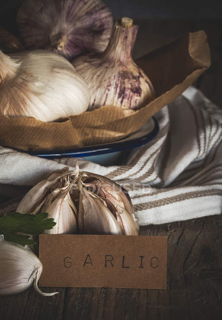 Still life of fresh garlic and plate cardboard sign with lettering — Stock Photo