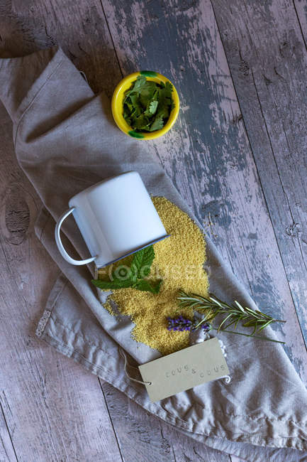 Mug on side with spilled Couscous on decorative Napkin at Wooden Table — Stock Photo