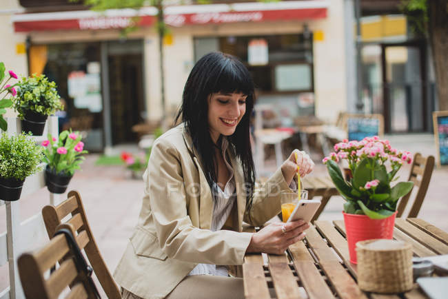 Femme utilisant un smartphone à la table de terrasse — Photo de stock