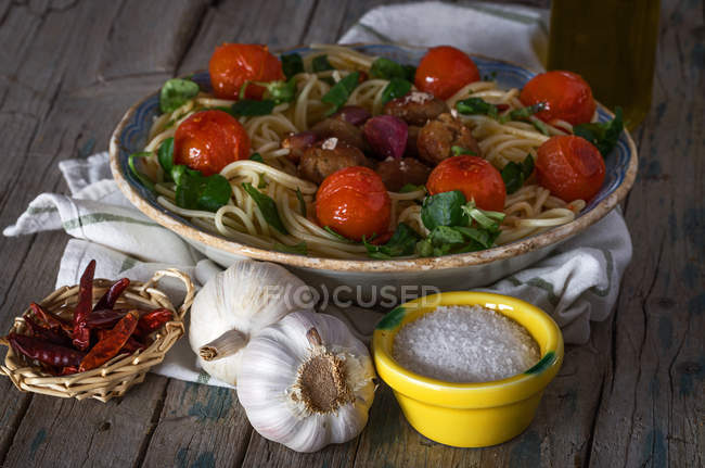 High angle view of spaghetti with meatballs and cherry tomatoes on plate served with spices and garlic — Stock Photo