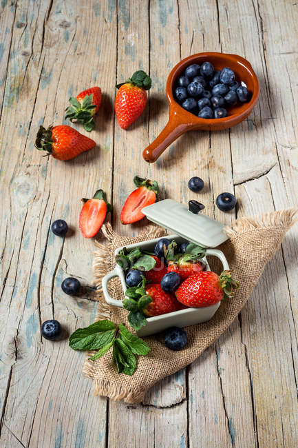 Mix of strawberries and blueberries on old wooden table — Stock Photo