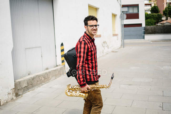 Jazzman andando com sax e olhando para a câmera — Fotografia de Stock