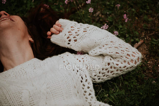 Crop ragazza zenzero sdraiato sull'erba e ridendo — Foto stock