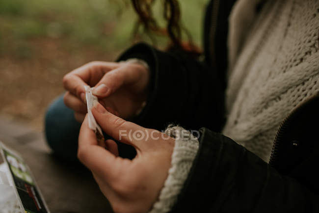 Colheita de mãos femininas rolando cigarro na natureza — Fotografia de Stock