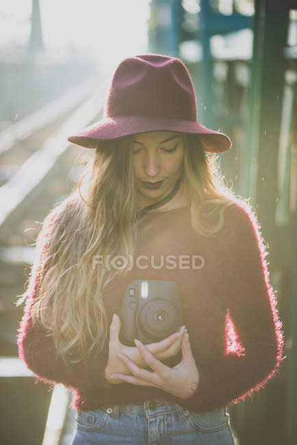 Дівчина в капелюсі за допомогою полароїдної камери — стокове фото