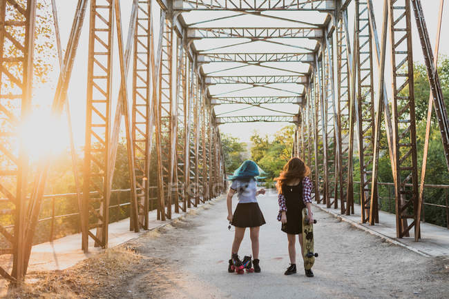 Девушки стоят на мосту со скейтбордами — стоковое фото