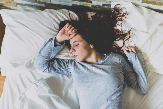 Femme en pyjama gris dormant sur des oreillers — Photo de stock