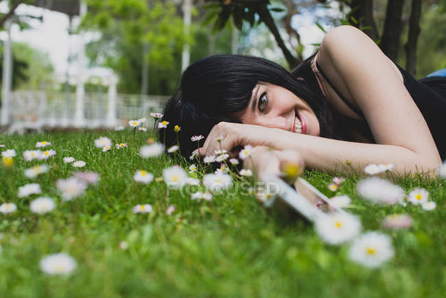 Donna sdraiata sull'erba con fiori di camomilla — Foto stock