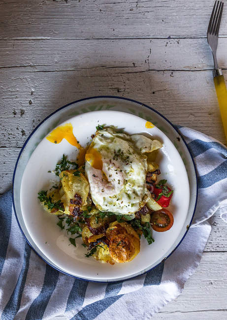Прямо над тарелкой с жареным яйцом и картошкой в сельской тарелке — стоковое фото