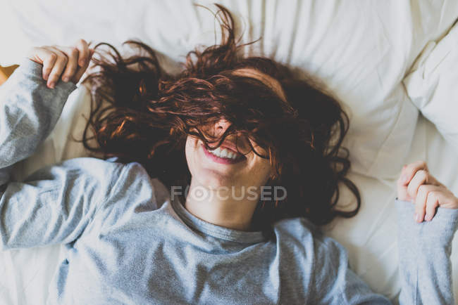 Menina deitada na cama com o rosto coberto de cabelo — Fotografia de Stock