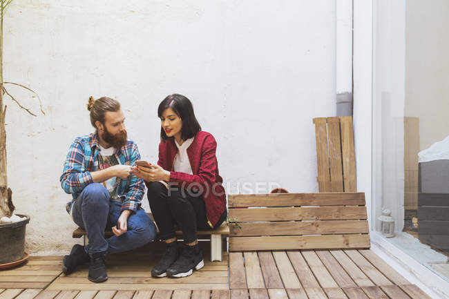 Paar sitzt und nutzt Smartphone — Stockfoto