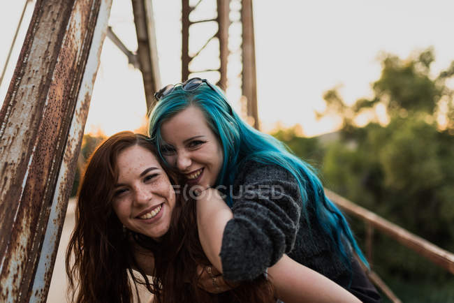 Mädchen befreit Freundin auf dem Rücken und schaut in die Kamera — Stockfoto