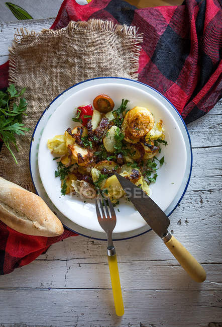 Directly above view of plate with rural dinner and bread on rustic table — Stock Photo