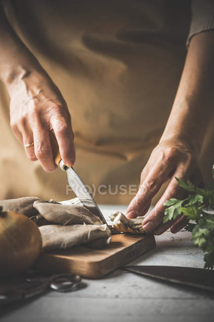 Close up of female slicing pleurotus mushrooms on wooden board with knife — Stock Photo