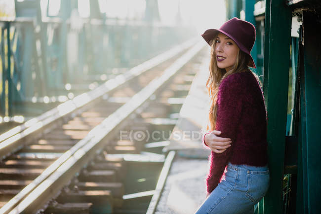Fille sur le pont ferroviaire et regardant la caméra — Photo de stock