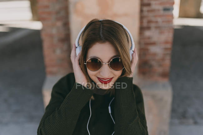 Chica en auriculares sonriendo a la cámara - foto de stock