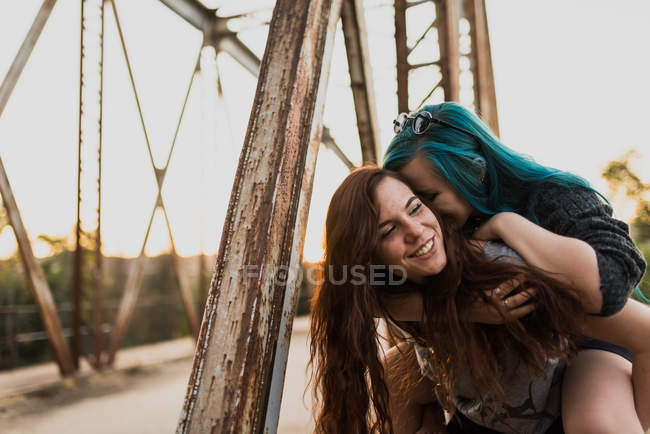 Chica liberando amigo en la espalda en el puente - foto de stock