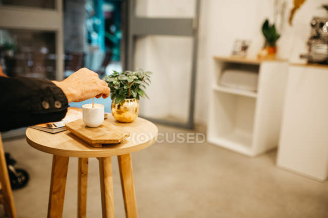Cosecha mano mezclando café con cuchara en la cafetería moderna - foto de stock