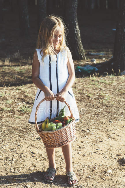 Anonymous child with basket of fruit — Stock Photo