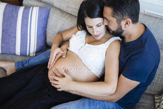 Padres felices abrazando a su hijo aún no nacido, esperando por el momento en el vientre de las madres. - foto de stock