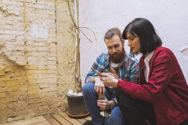 Paar sitzt und nutzt Smartphone — Stockfoto
