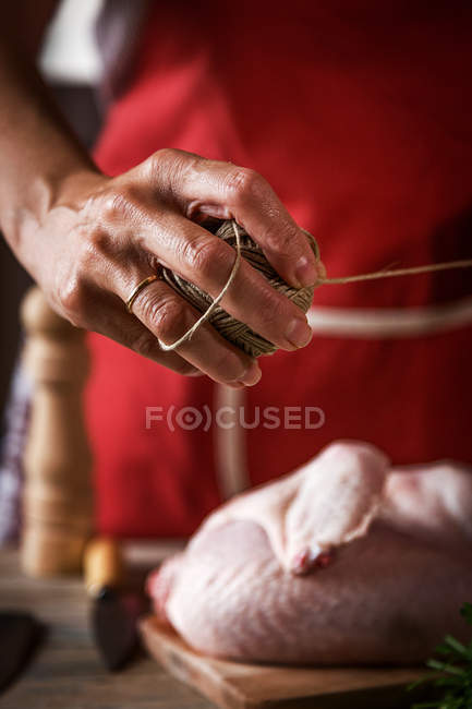 Primer plano de la mujer preparando pollo para asar con cuerda - foto de stock