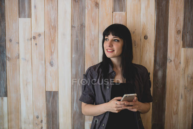 Mujer usando smartphone y mirando hacia otro lado . - foto de stock