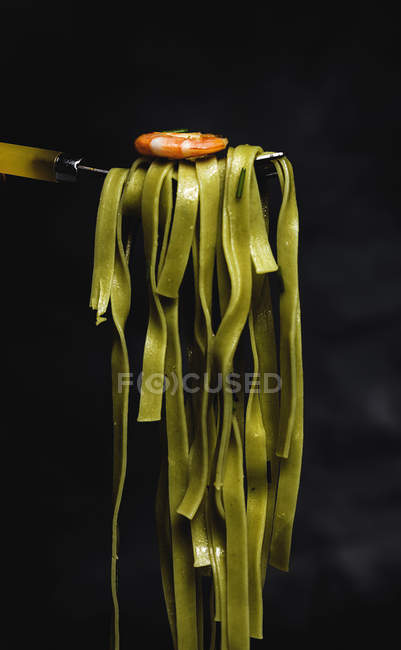 Tagliatelle verde com frutos do mar em garfo no fundo preto — Fotografia de Stock